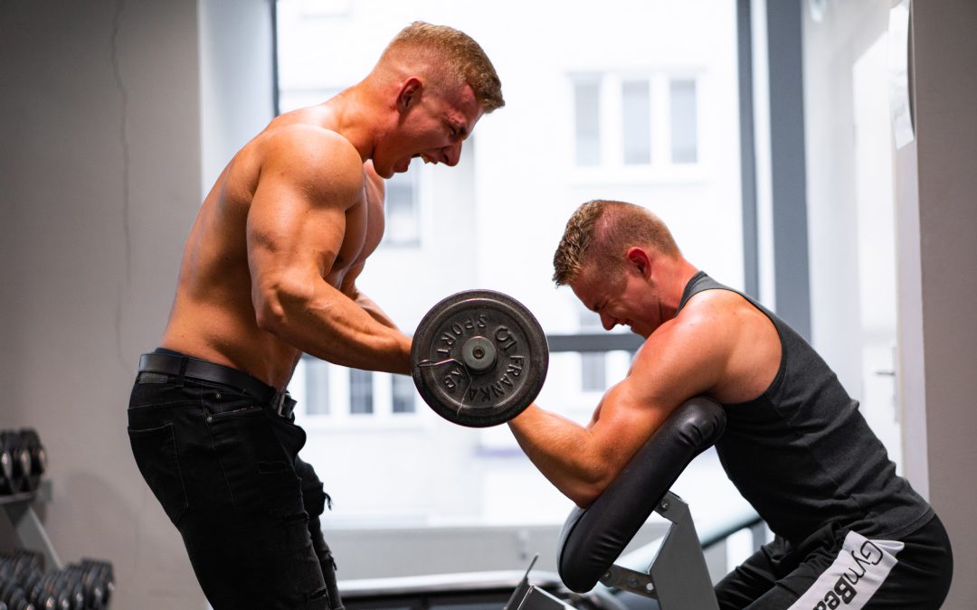 Tréner asistuje pri cvičení bicepsu s jednoručnou činkou